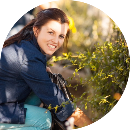 A woman smiles at the camera as she picks up trash off of the street.