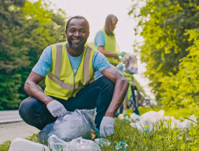 Two volunteers on the side of the road picking up trash.