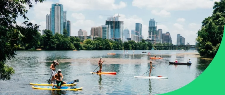 Paddle boarders on Lady Bird Lake with a view of downtown Austin.