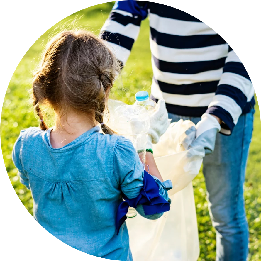 A little girl helps a woman in a striped shirt pick up trash outdoors.