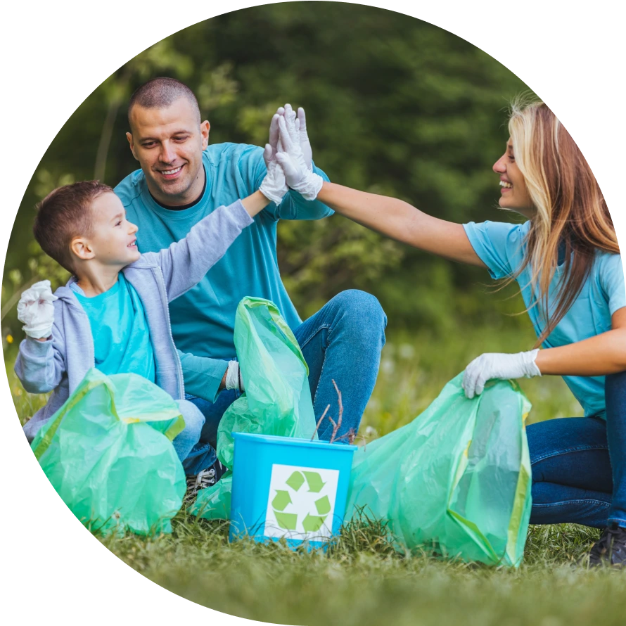 A family high fiving over green trash bags at an outdoor park.