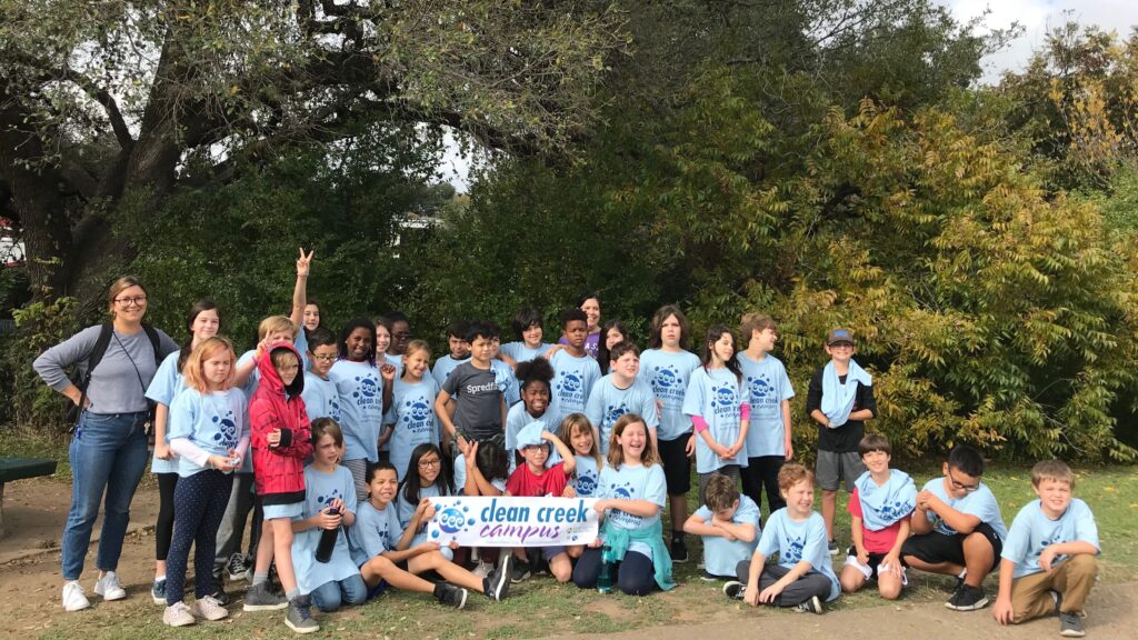 Photo of a group of students holding up a sign reading "Clean Creek Campus".