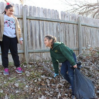 Recognition for Leadership & Education 8 Two young girls cleaning up leaves and branches.
