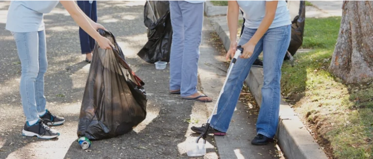 Group of volunteers picking trash up off of the street during Love Where You Live Day.