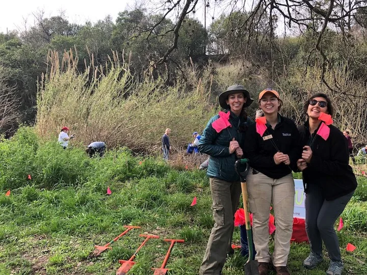 Three Keep Austin Beautiful volunteers posing in front of a trash pickup area.