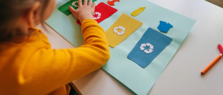 A girl in a yellow cardigan learning about recycling and composting.