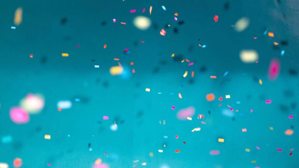 Rainbow confetti falling down on a teal background.