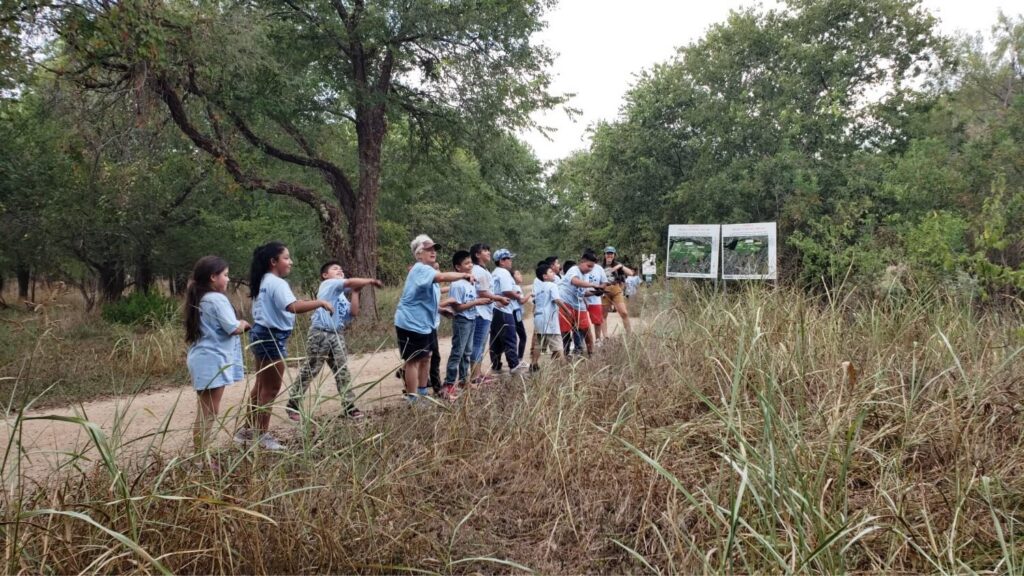 Keep Austin Beautiful volunteers throwing seed balls into a grassy field.