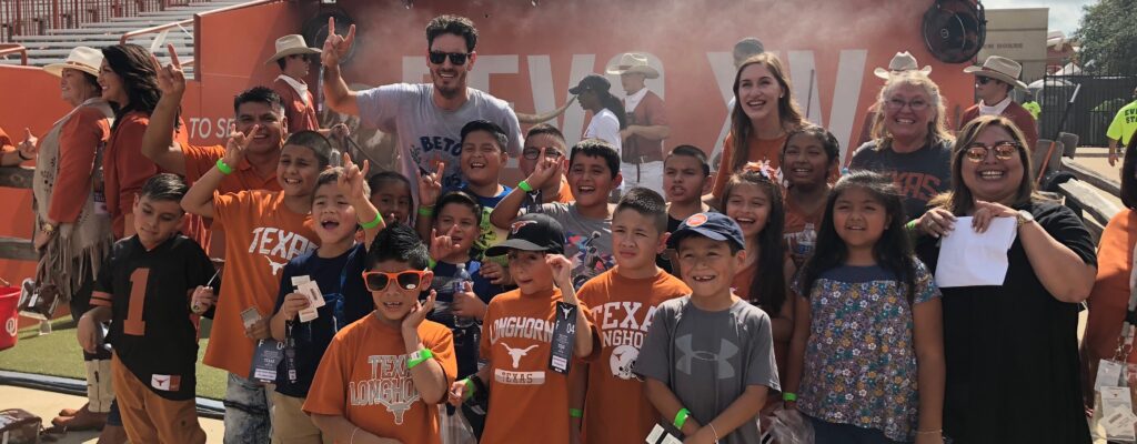 Group of children from Baty Elementary in Longhorn gear at a football game.